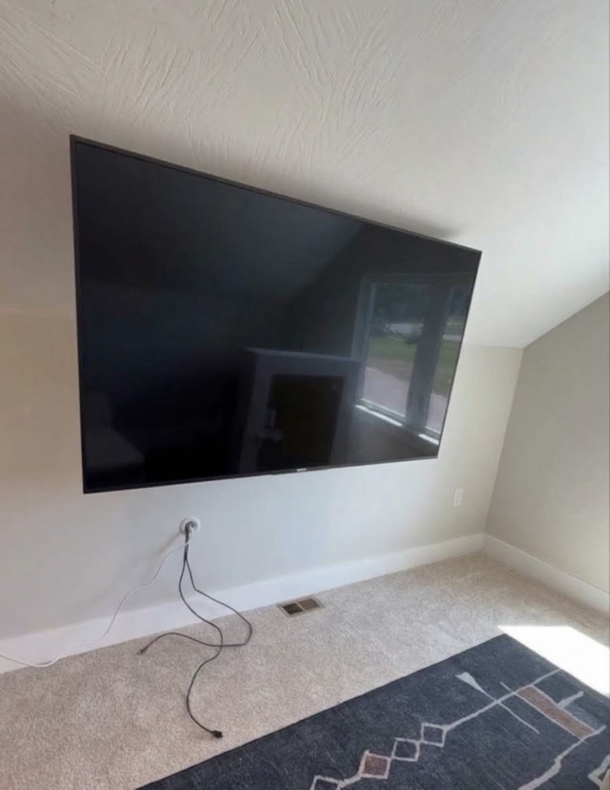 TV mounted over a stone fireplace below a rustic windmill ceiling fan