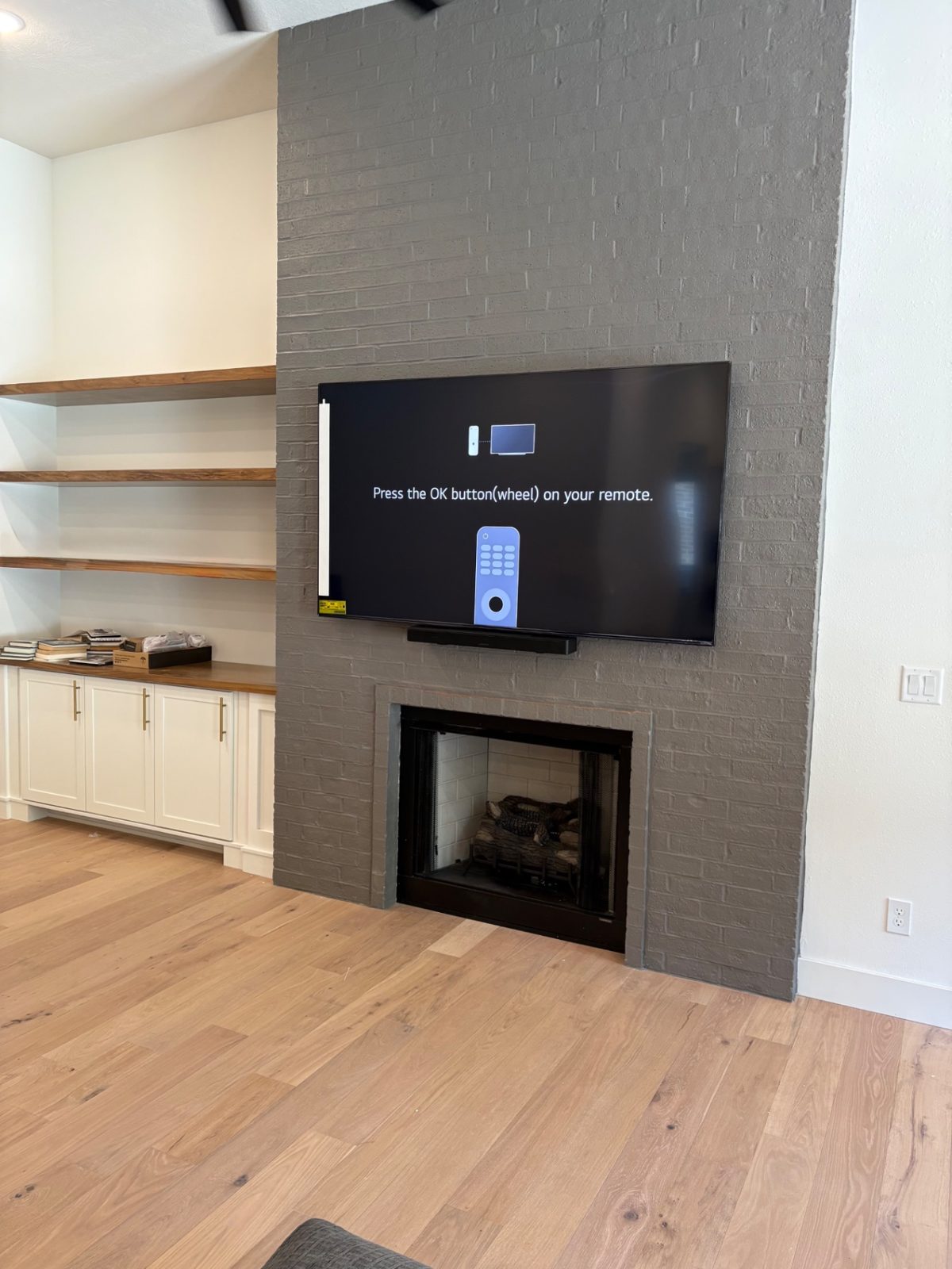 TV mounted over a charcoal painted brick fireplace